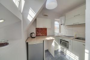 een keuken met witte kasten en een spoelbak bij Dream Loft Motlava River in Gdańsk