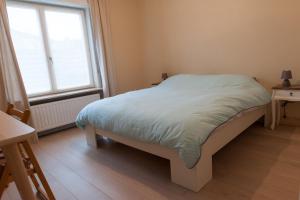 een slaapkamer met een bed en 2 ramen bij De Witte Parel in Oostduinkerke