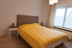 una camera da letto con un letto con una coperta a strisce gialle di De Witte Parel a Oostduinkerke