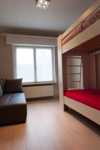 a bedroom with two bunk beds and a couch at De Witte Parel in Oostduinkerke