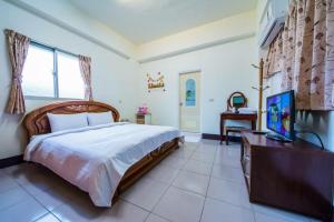 Un dormitorio con una cama y un televisor. en Happy Garden Homestay, en Taitung