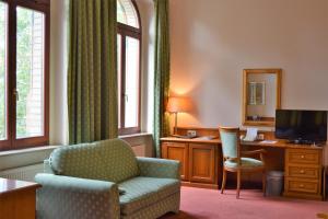 a living room with a chair and a desk at Hotel Artushof in Dresden