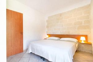 サン・フォカにあるCasa Vacanze Mare e Uliviのレンガの壁の客室の白いベッド1台