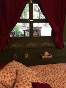 a bedroom with a bed and a window with red curtains at Les Insolites in Watronville