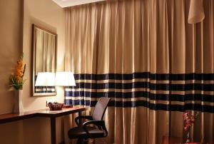 um quarto com uma secretária, uma cadeira e uma cortina em Ramoji Film City- Sitara Luxury Hotel em Pedda Ambarpet