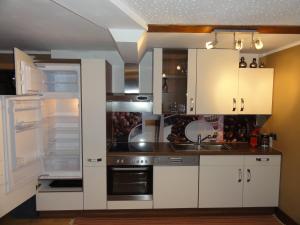 a kitchen with white cabinets and an open refrigerator at Familienferienwohnung Manuela Scherer in Neukirchen am Großvenediger