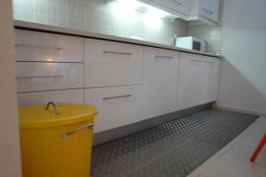 a kitchen with white cabinets and a yellow trash can at Clemens in Málaga