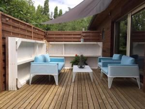 un patio con sillas azules y una mesa en una terraza de madera en Les Rêveries, en Chazé-sur-Argos