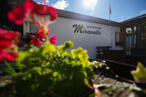 ein Schild auf einem Gebäude mit Blumen im Vordergrund in der Unterkunft Agriturismo Miravalle in Brusio