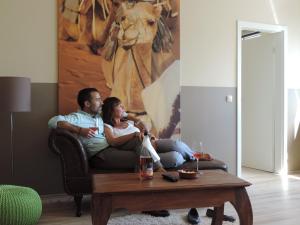 a man and woman sitting on a couch in a living room at Hotel Sandmanns am Dom in Cologne