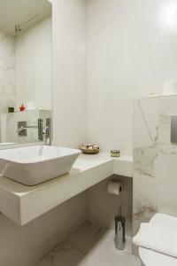 a white bathroom with a sink and a mirror at Candia Studios & Rooms in Heraklio Town