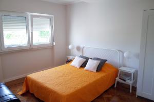 1 dormitorio con 1 cama con 2 almohadas y 2 ventanas en Lisbon Beach Apartments 3, en Costa da Caparica