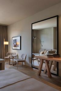a room with a bed, chair, table and a mirror at Hotel Peralada Wine Spa & Golf in Peralada