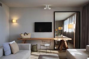 een woonkamer met een tafel en een televisie aan de muur bij Hotel Peralada Wine Spa & Golf in Peralada