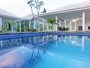 a swimming pool in front of a villa at Lombok Holiday Hotel in Kuta Lombok