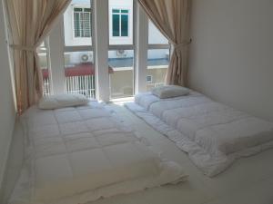 Duas camas num quarto com uma janela grande em Properties Homestay, Balik Pulau em Balik Pulau