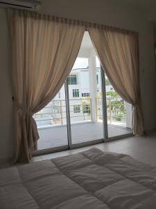 a bedroom with a large window with curtains and a bed at Properties Homestay, Balik Pulau in Balik Pulau