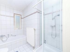 a white tiled bathroom with a shower and a tub at Apartment in Densberg with terrace in Densberg