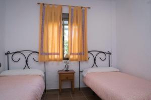 two beds in a room with orange curtains and a window at Apartamentos Hacienda Sajorami in Zahora +36 photos