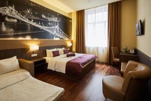 um quarto de hotel com duas camas e uma cadeira em 12 Revay Hotel em Budapeste