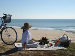 a girl sitting on a blanket on the beach at Hôtel Restaurant & Spa Plaisir in Le Bois-Plage-en-Ré