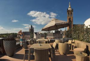 a woman standing on a balcony with a table and chairs at Hotel Dux in Roermond