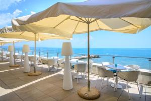een patio met tafels, stoelen en parasols bij Nympha Hotel, Riviera Holiday Club - All Inclusive & Private Beach in Goudstrand