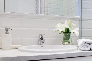 un lavabo con un jarrón de flores blancas en Elite Apartments Marine Mila Baltica, en Gdansk