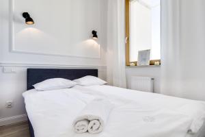 Un dormitorio con una cama blanca con toallas. en Elite Apartments Marine Mila Baltica, en Gdansk