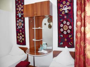 Pokój z czerwonymi zasłonami i stołem z zegarem w obiekcie Khiva Alibek B&B & Travel w mieście Chiwa