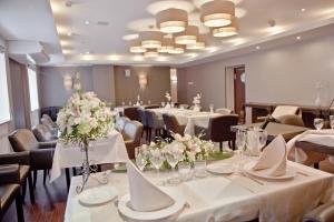 una habitación con mesas y sillas, mesas blancas y flores en Graf Orlov Hotel en Samara