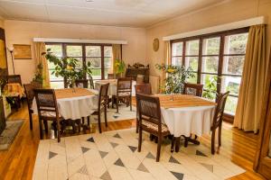 a dining room with tables and chairs and windows at Estancia Río de Los Ciervos in Punta Arenas