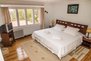 a bedroom with a white bed and a television at Estancia Río de Los Ciervos in Punta Arenas