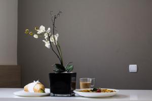 una mesa con dos platos de comida y un jarrón con flores en Garni Hotel Krevet&Dorucak, en Niš
