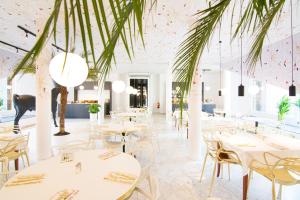 a restaurant with white tables and chairs and palm trees at MABI City Centre in Maastricht