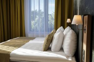 a hotel room with a bed with pillows and a window at Centennial Nexus Hotel Tallinn in Tallinn