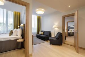 a hotel room with a bed and a couch and a chair at Centennial Nexus Hotel Tallinn in Tallinn