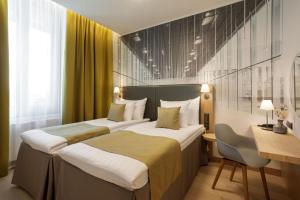a hotel room with two beds and a desk and a desk at Centennial Nexus Hotel Tallinn in Tallinn