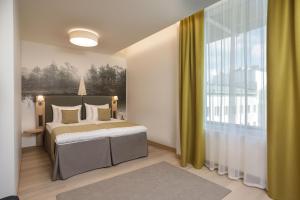 a bedroom with a bed and a large window at Centennial Nexus Hotel Tallinn in Tallinn