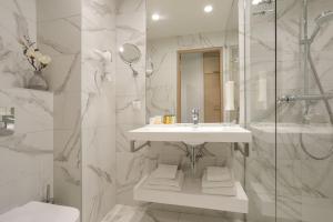 a white bathroom with a sink and a shower at Centennial Nexus Hotel Tallinn in Tallinn