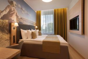 a hotel room with a bed and a television at Centennial Nexus Hotel Tallinn in Tallinn