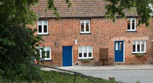 a red brick building with blue doors on a street at Blue Bell Cottage in Ollerton