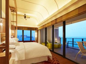 a bedroom with a large bed and a balcony at Sheraton Okinawa Sunmarina Resort in Onna