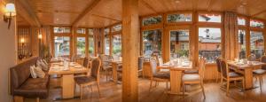 ツェルマットにあるホテル シェミニの木製のテーブルと椅子、窓のあるレストラン