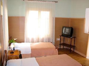 a room with two beds and a tv and a window at Earini Rooms And Apartments in Chania