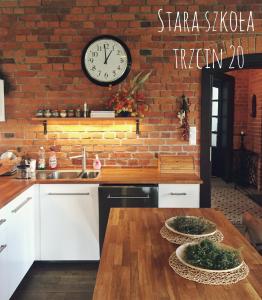 a kitchen with a clock on a brick wall at Stara Szkola Trzcin 20 in Trzcin