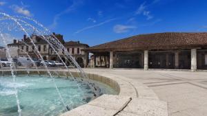 a fountain in a plaza in front of a building at VVF Gers Gascogne in Mauvezin