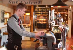 a man standing at a counter in a coffee shop at Pine Marten, Dunbar by Marston's Inns in Dunbar