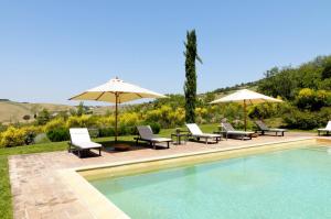 a swimming pool with chairs and umbrellas next to at Agriturismo Le Macchie in Monticchiello