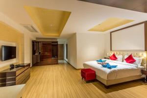乌贾因Hotel Abika Elite的一间带大床和电视的卧室